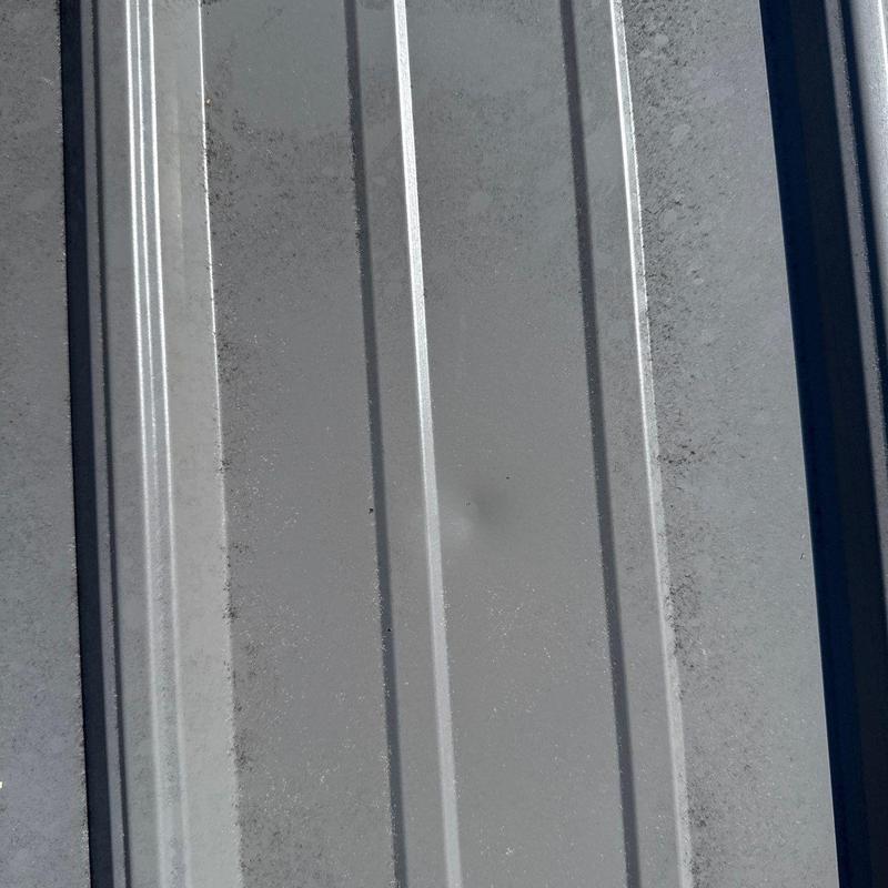 Metal roof panel with hail damage dent