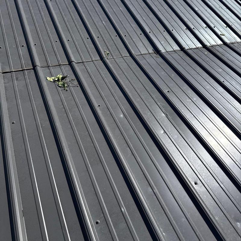 Metal roof panels with hail damage and debris on surface