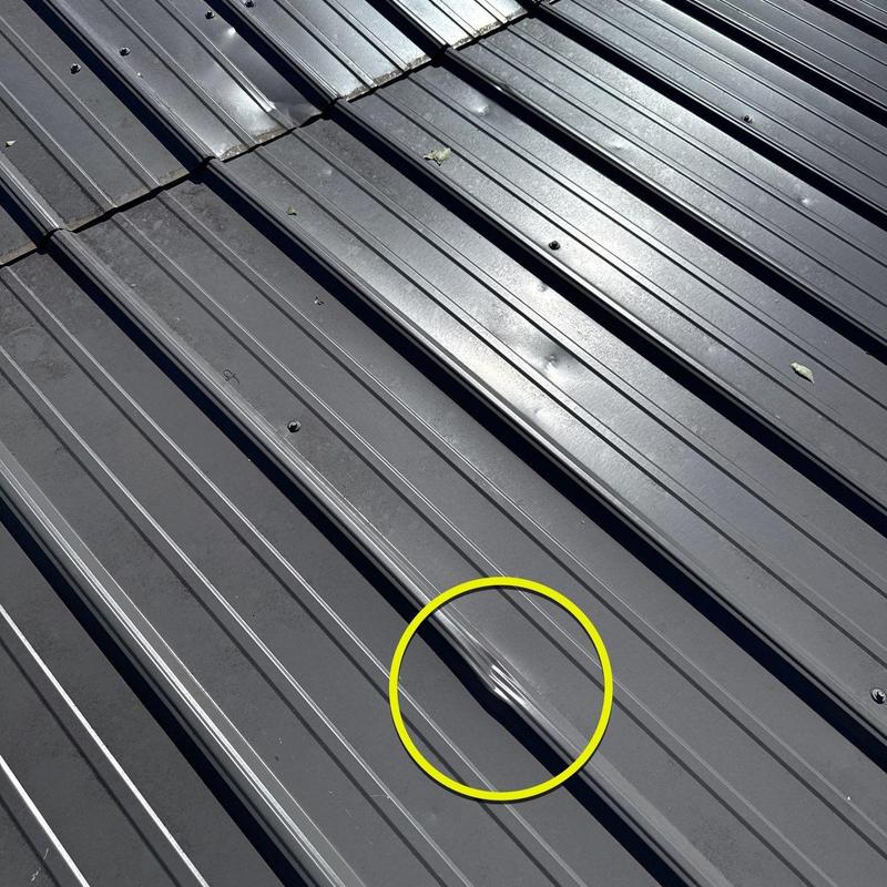 Metal roof panel with hail damage dent highlighted