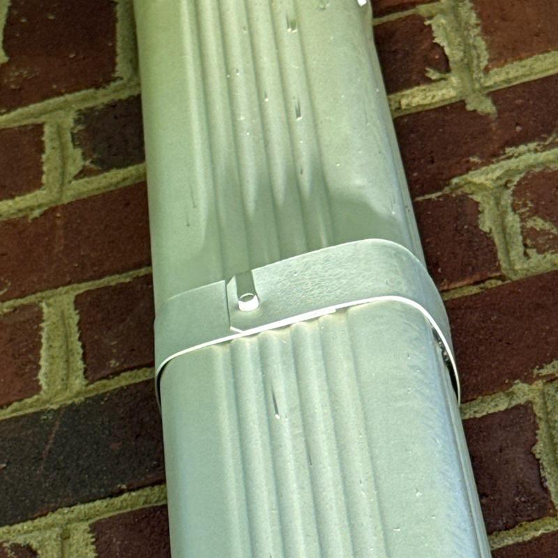 Metal downspout detail secured to brick wall exterior