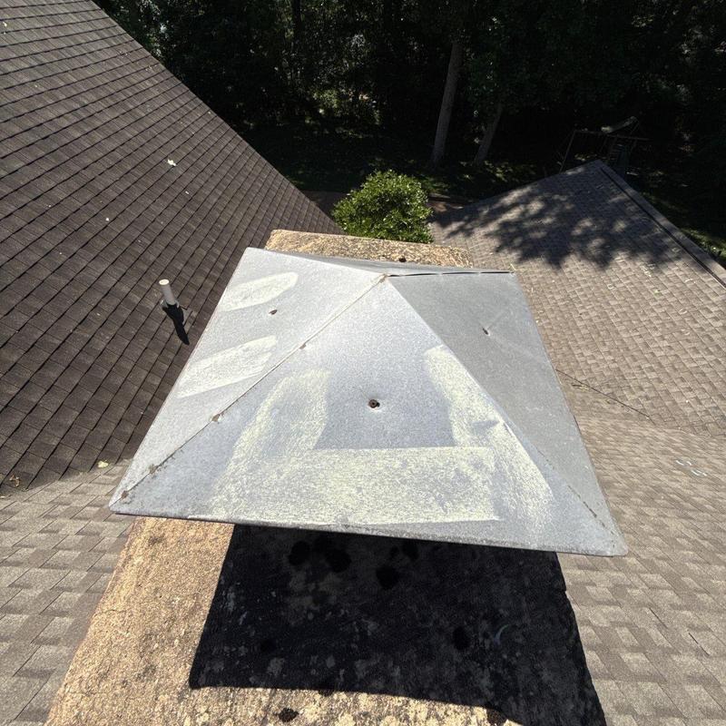 Chimney metal cap with hail impact marks on roof