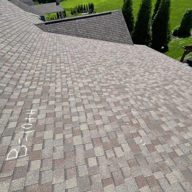 Asphalt shingles with hail damage markings on roof