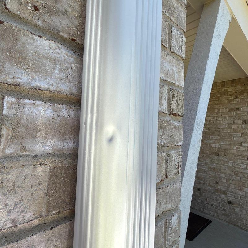 Vinyl downspout dent near brick wall exterior