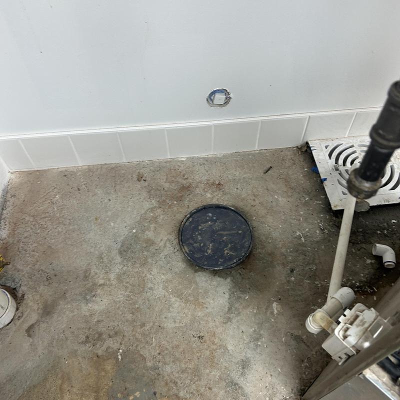 Main line sewer cleanout with surrounding floor and pipes Main line sewer cleanout with surrounding floor and pipes