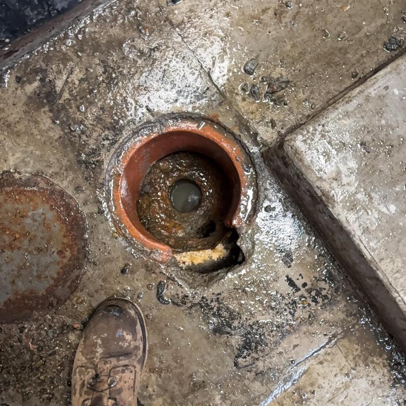 Laundry floor drain with removed pipe section and concrete cutout