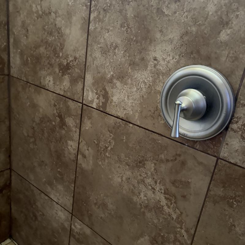 Shower valve handle on textured tile wall