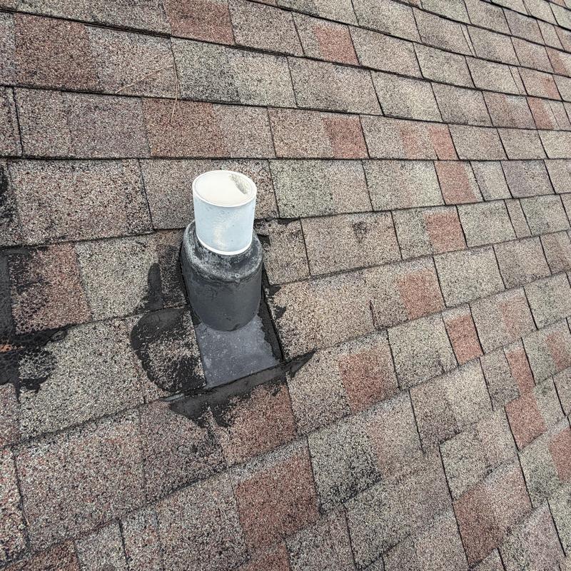 Pipe boot with damaged shingles on asphalt roof