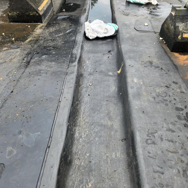 EPDM roof seam and surface with cleaning cloth EPDM roof seam and surface with cleaning cloth