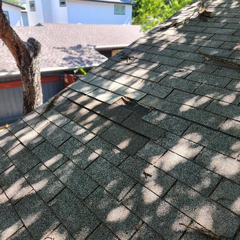 Roof shingles with visible damage and missing sections Roof shingles with visible damage and missing sections
