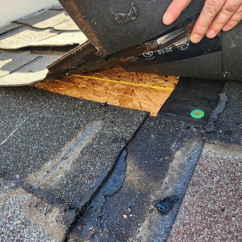 Roof decking exposed under lifted shingles and underlayment