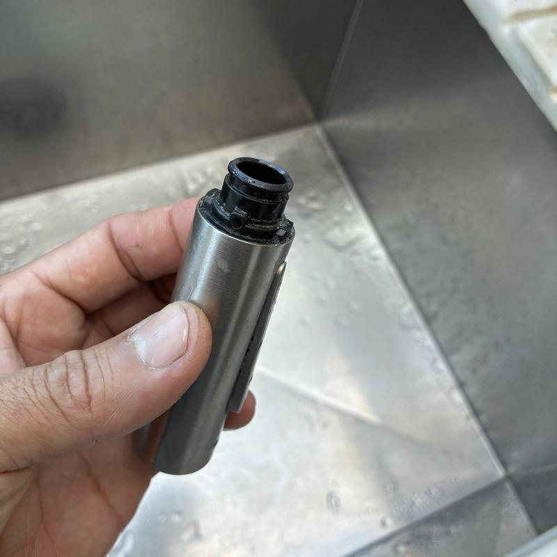 Bathroom faucet cartridge held by hand above sink basin