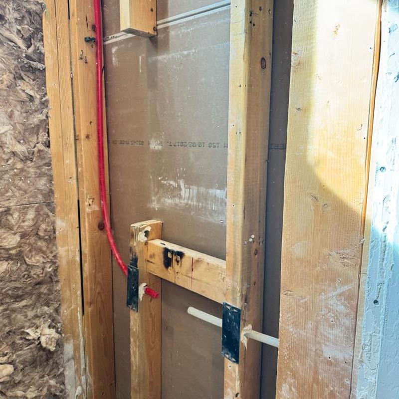 Shower valve plumbing rough-in with red and white pipes