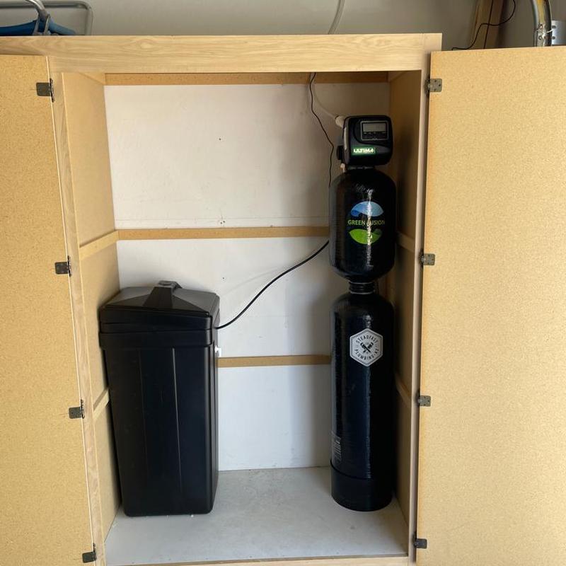 Water softener system installed in utility cabinet
