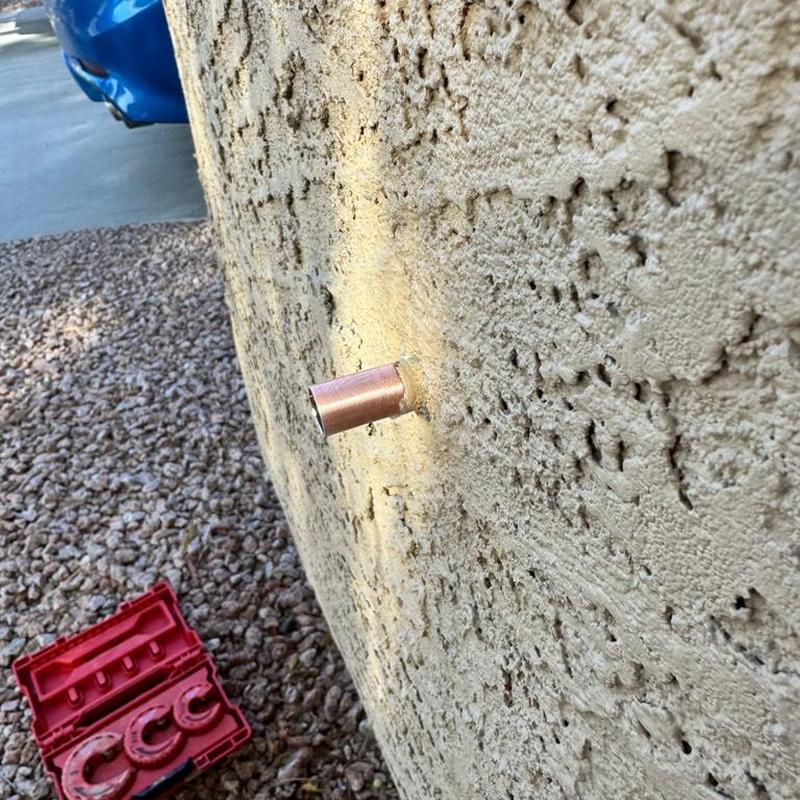 Copper hose bib pipe protruding from stucco wall exterior