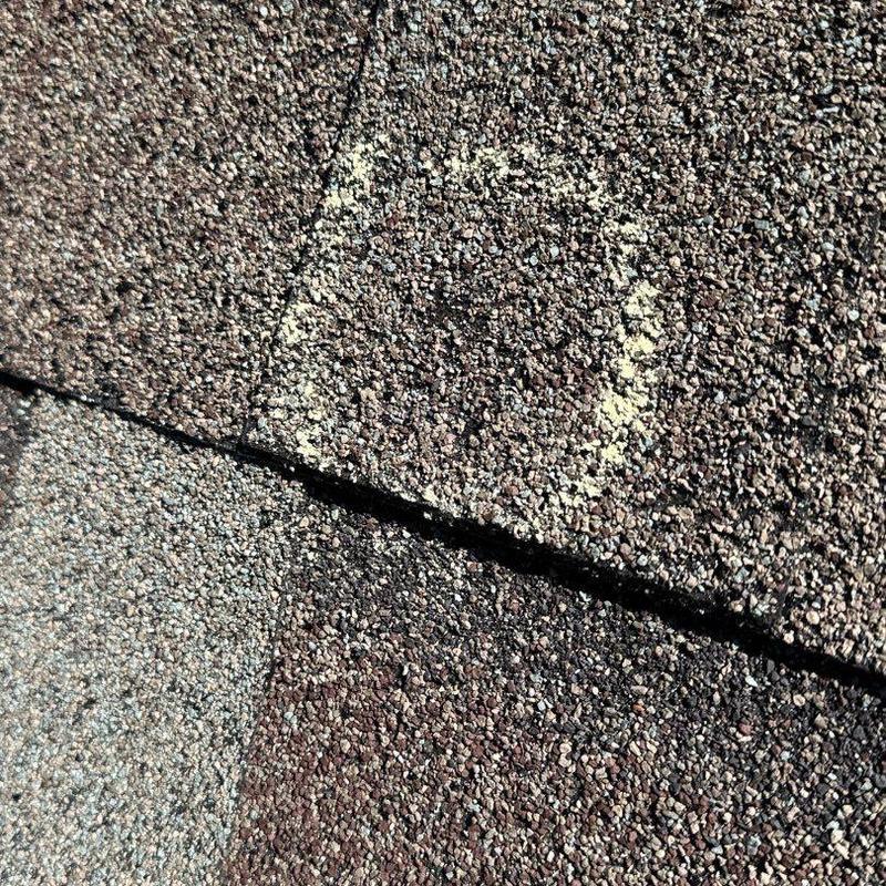 Asphalt roofing shingle with hail damage marked for repair