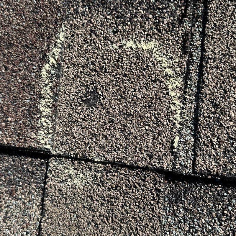 Asphalt shingle with hail damage marked for repair