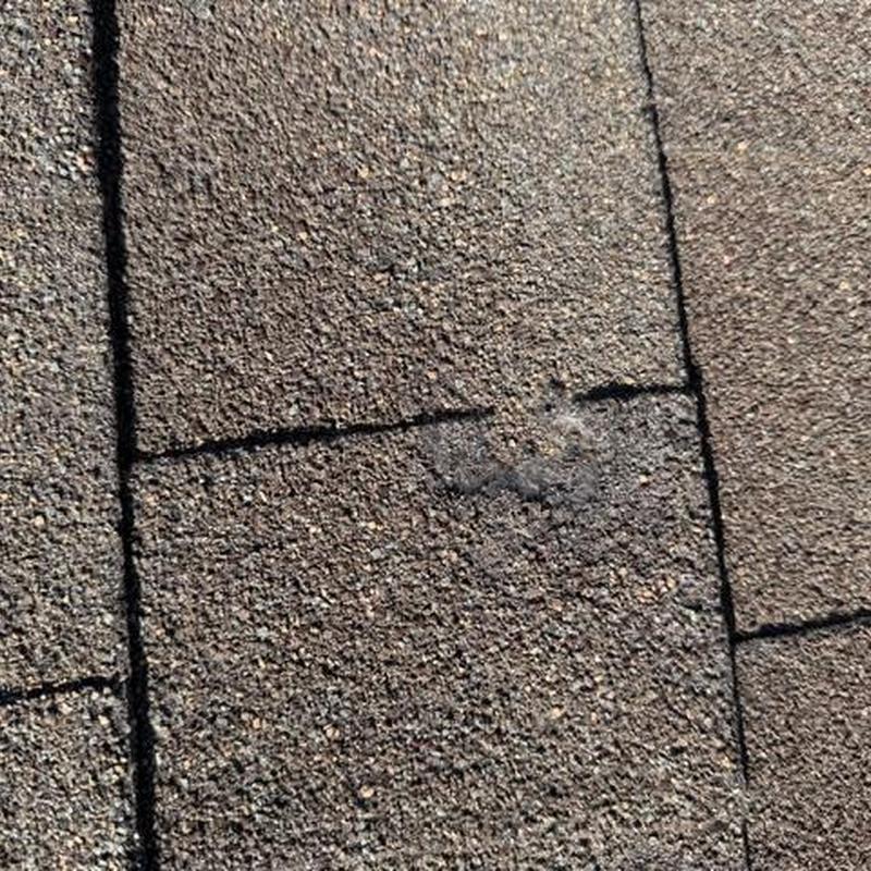 Asphalt roof shingles close-up with damage spot