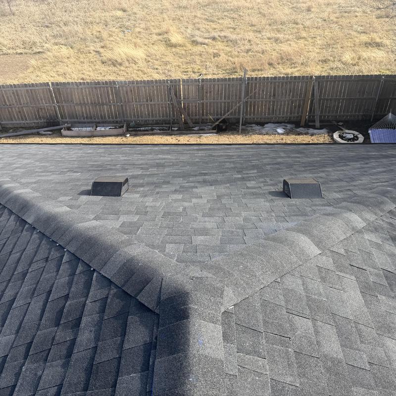 Gray shingle roof with ridge vents and fence background