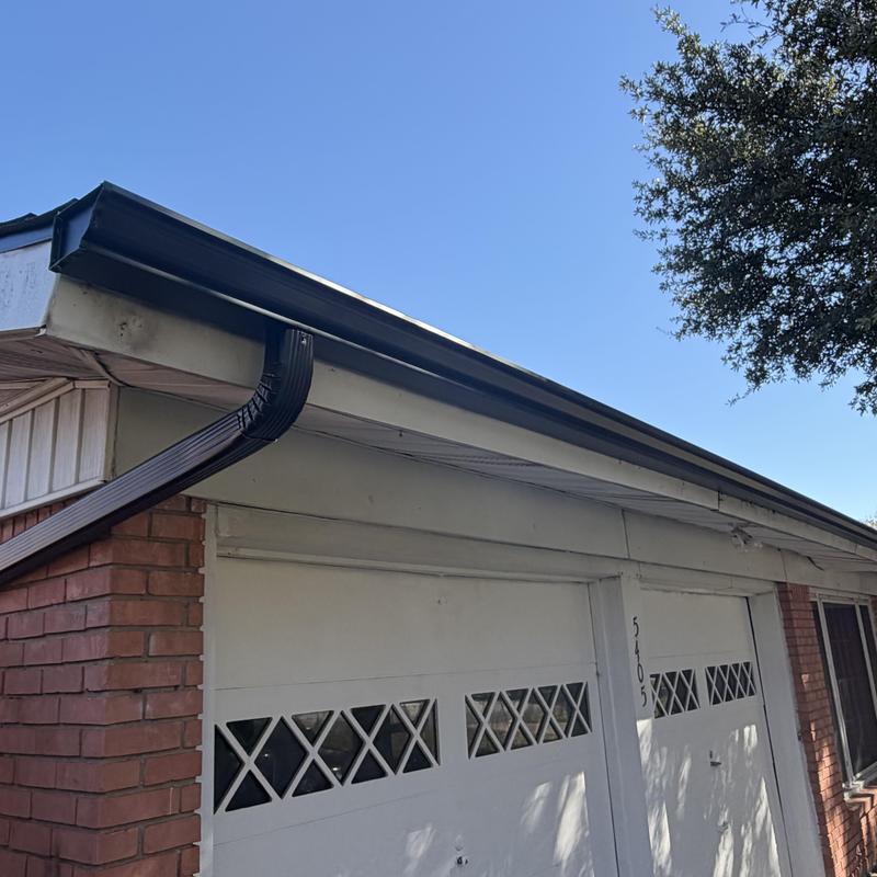 Black aluminum gutter system with downspout on brick home