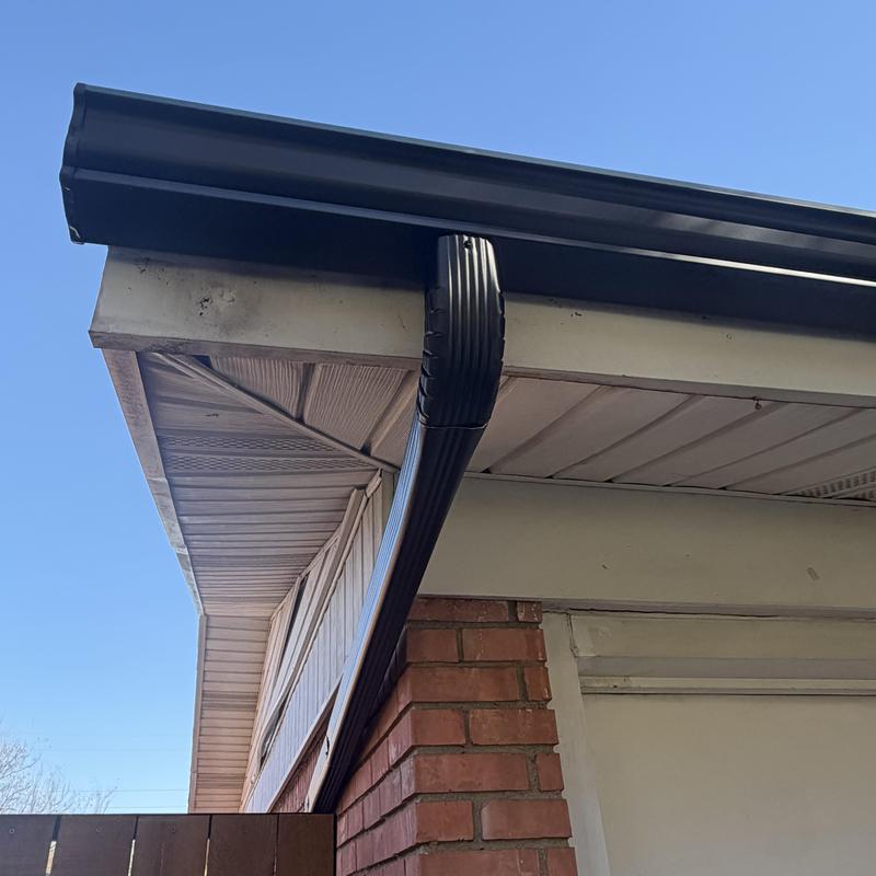 Black gutter system and downspout on brick wall