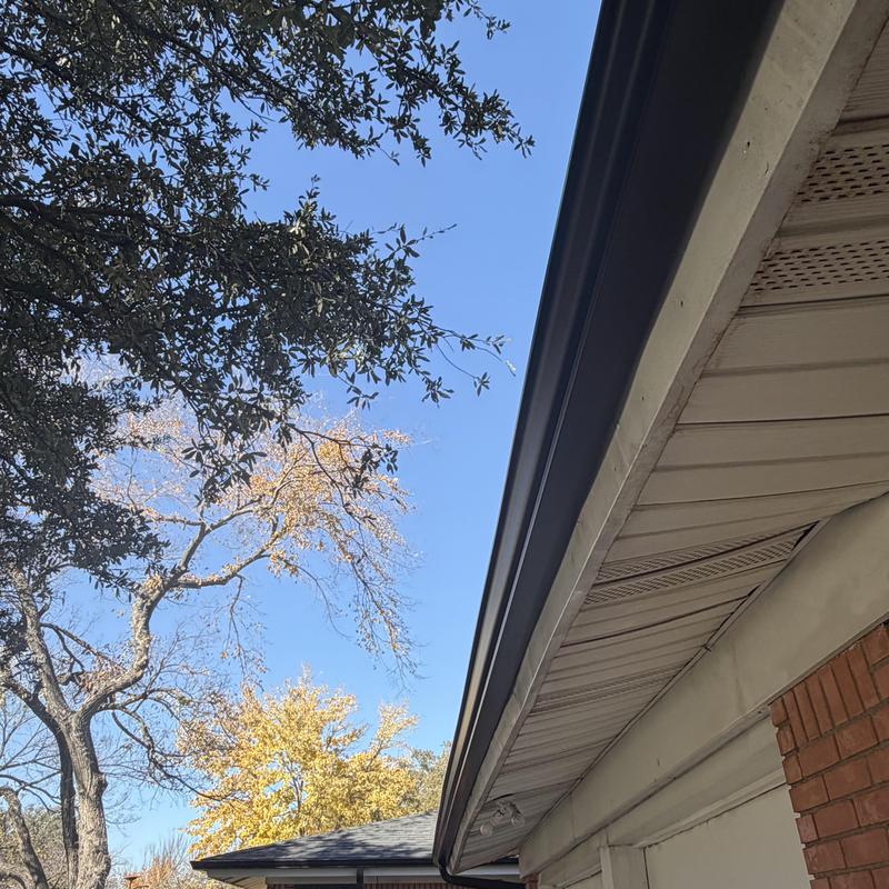 Black gutter installation on residential roof edge