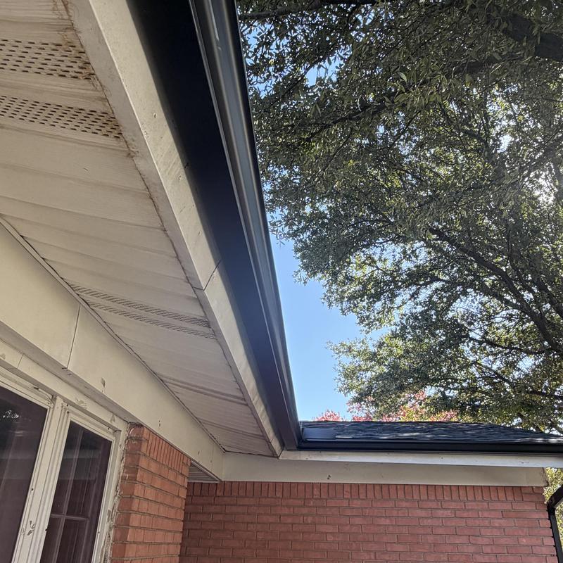 Black gutter installation on brick home exterior