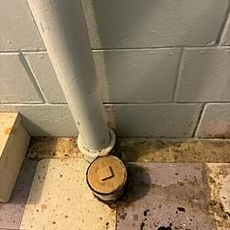 Sewer line cleanout pipe in basement corner