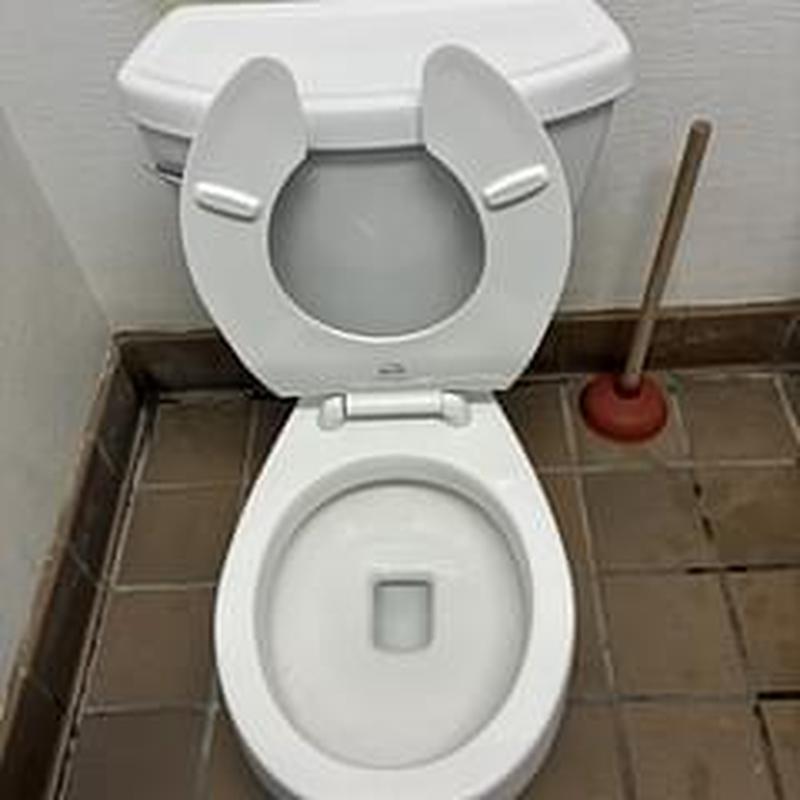Toilet bowl with open seat and plunger nearby