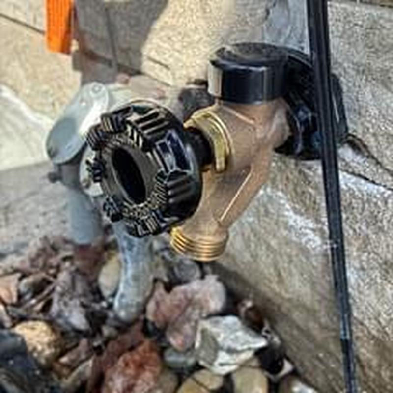 Outdoor hose bib installation on stone wall exterior