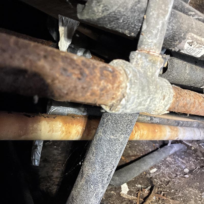 Rusty gas piping and connections under home in crawl space