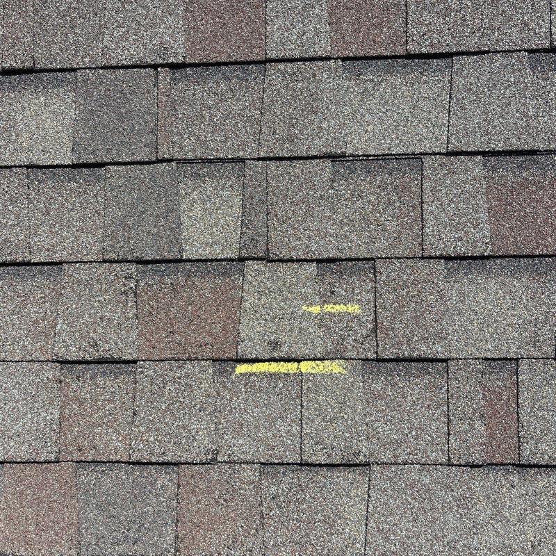 Roof shingles with hail damage marked in yellow
