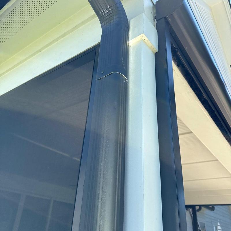 Metal downspout with dented section on house corner