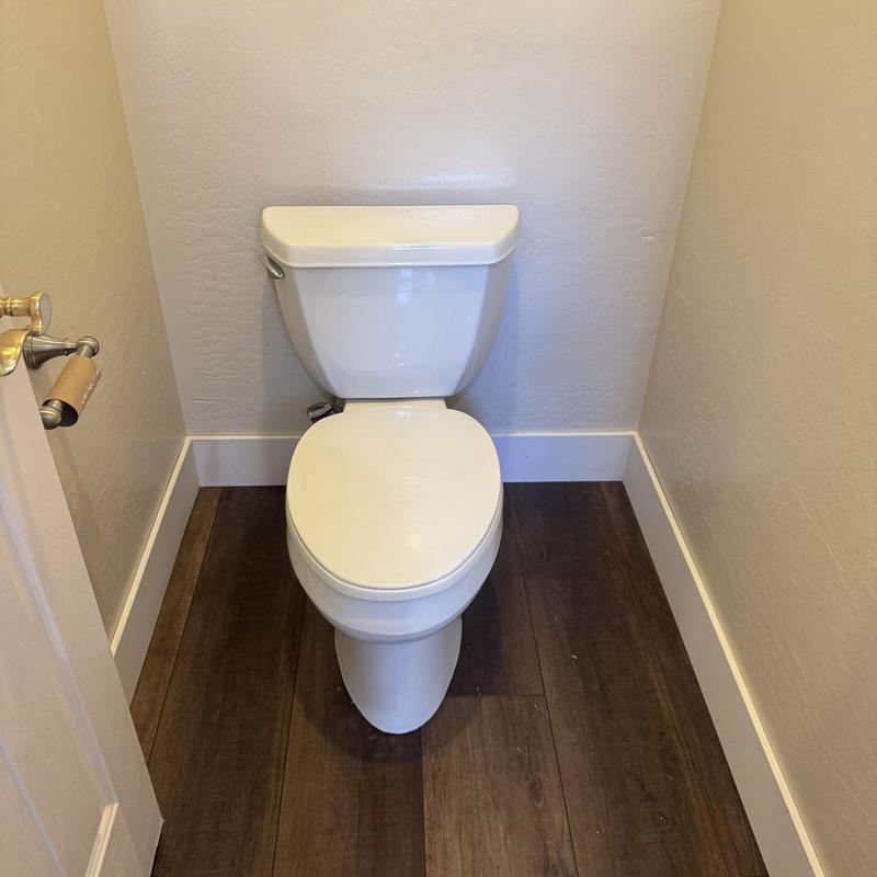 Toilet installation in small bathroom with wood floor