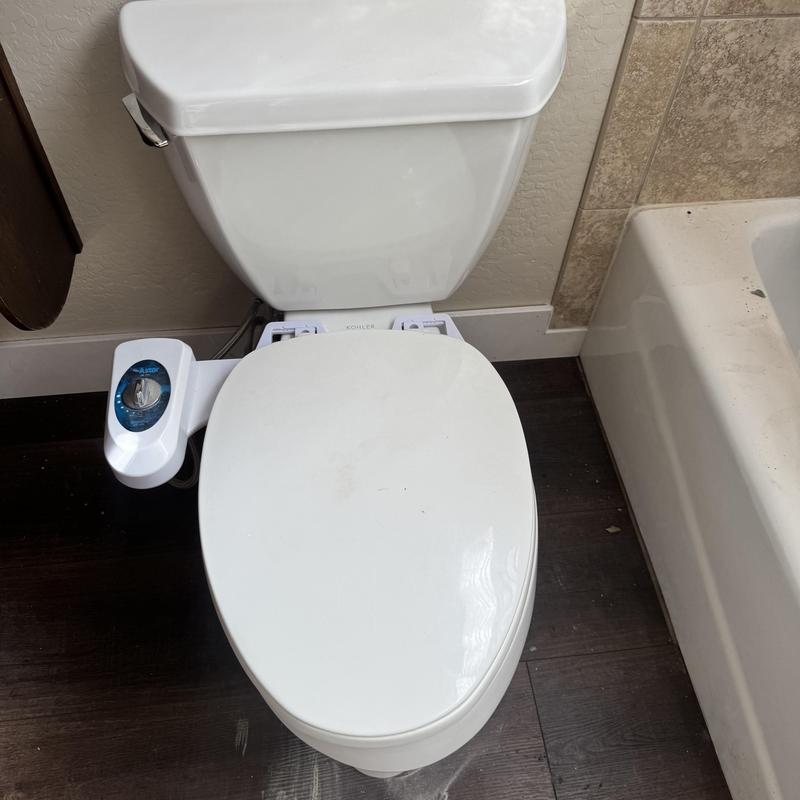Toilet with bidet attachment installed in bathroom