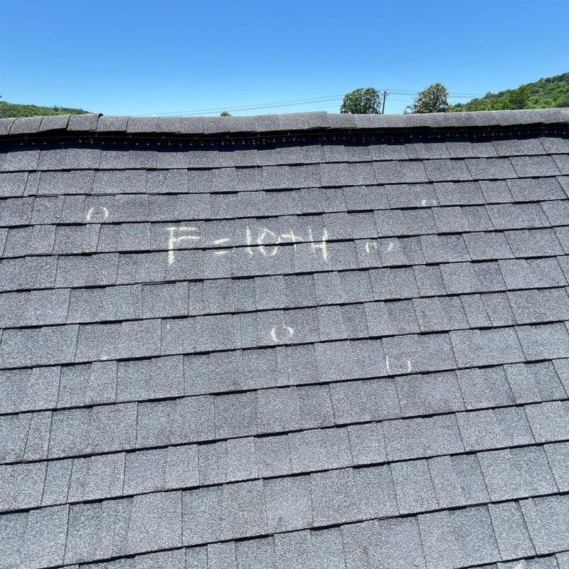 Roof shingles with chalk markings from hail damage inspection