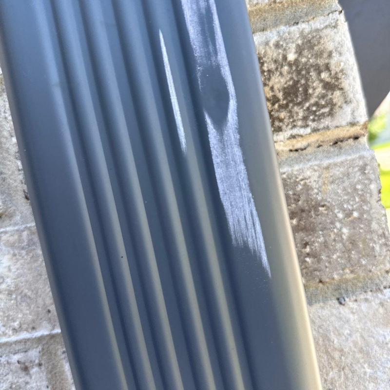 Metal gutter with scrape damage on exterior brick wall