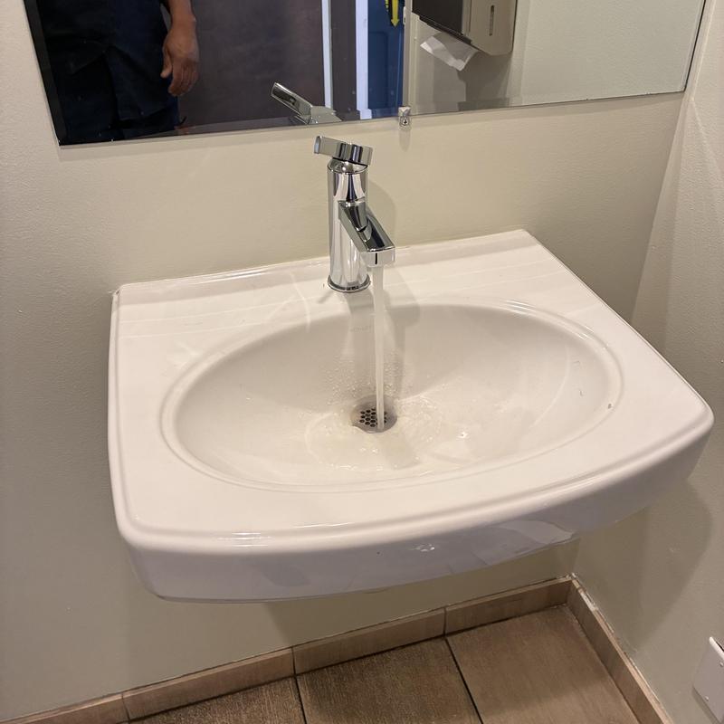 Basin faucet flowing water in warehouse bathroom