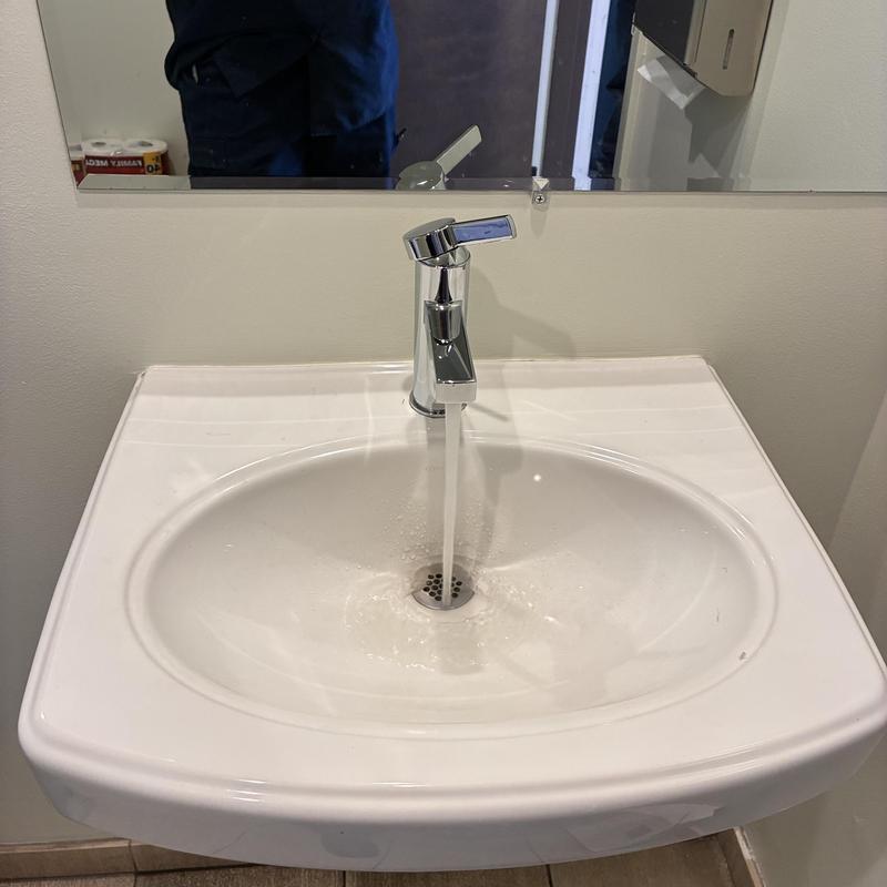Basin faucet with running water in warehouse bathroom