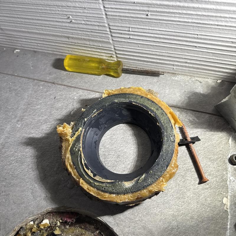 Toilet flange and wax ring with screwdriver on floor