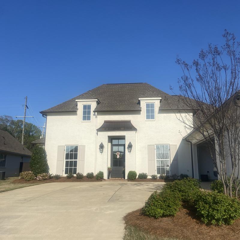 New gutters and downspouts on white brick house