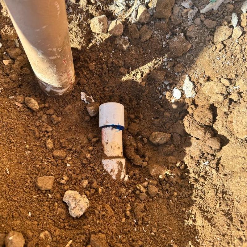 PVC drain pipe capped and surrounded by dirt and rocks PVC drain pipe capped and surrounded by dirt and rocks
