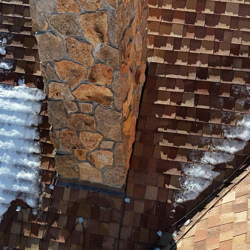 Asphalt shingle roof and heat tape near stone chimney Asphalt shingle roof and heat tape near stone chimney