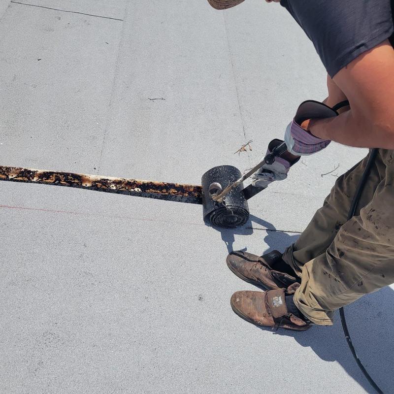 Modified bitumen roll being torched on flat roof repair