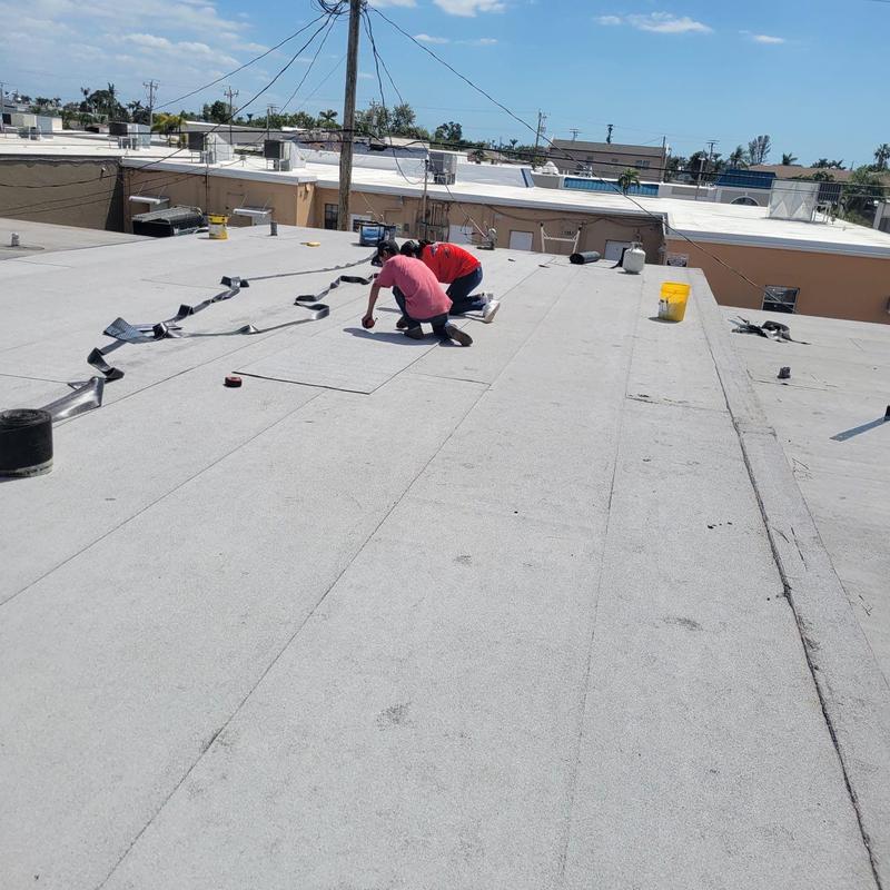 Modified bitumen flat roof with workers repairing membrane