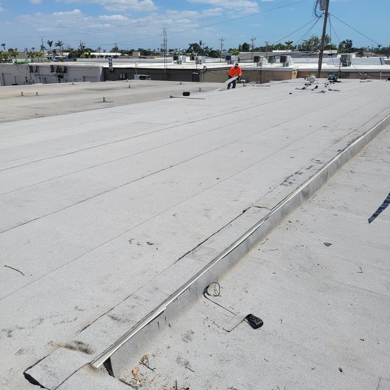 Modified bitumen roof membrane with worker on flat roof