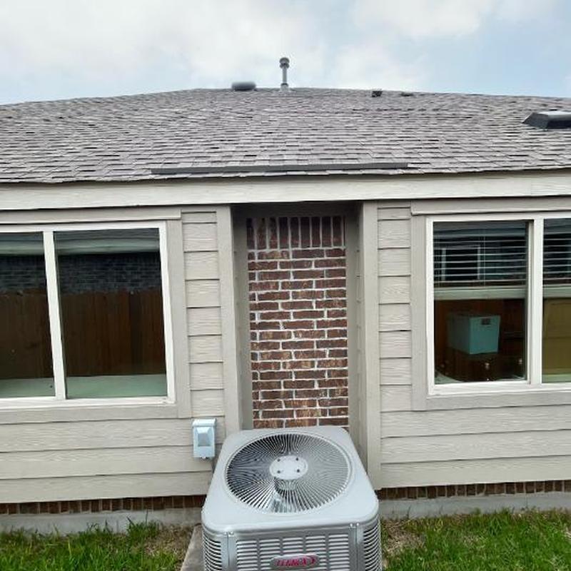 Air conditioner unit outside beige house with windows