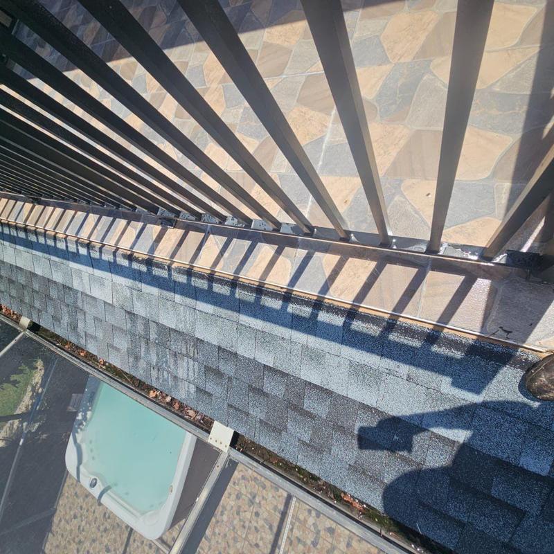 Shingle roof edge near metal railing showing wear