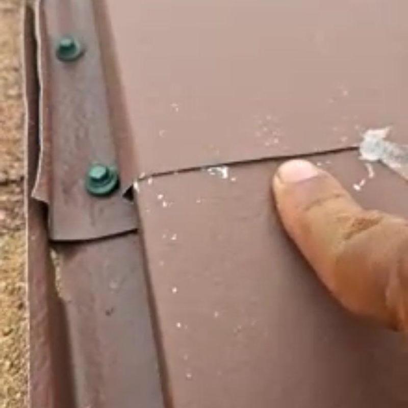Metal roof panel close-up with finger pointing defect