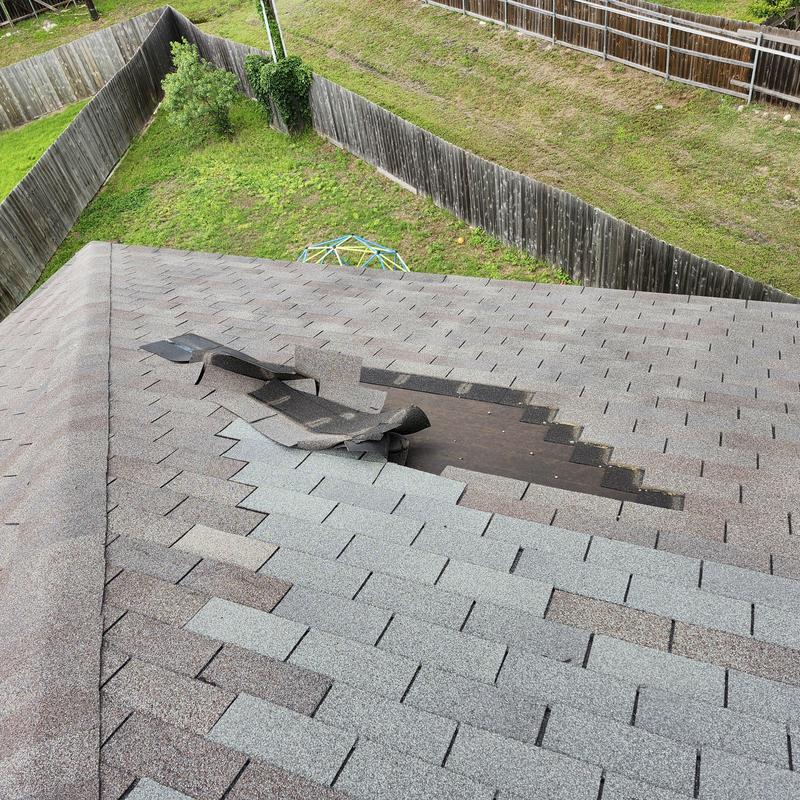 Weather gray shingles with wind damage on roof