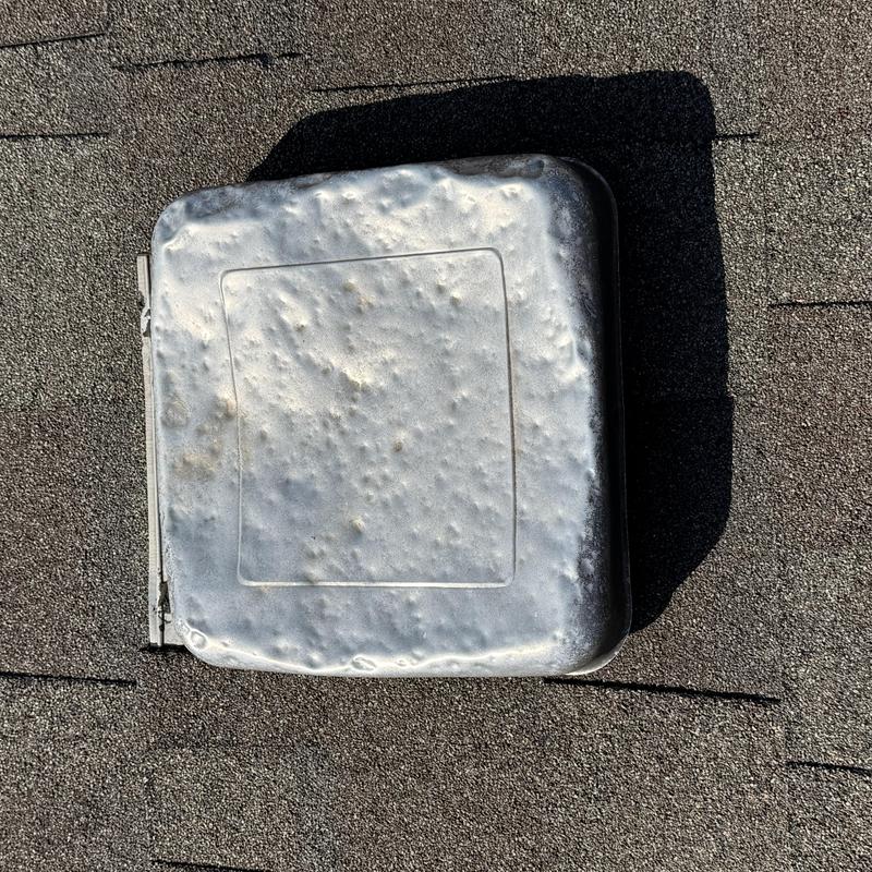 Metal roof vent with hail damage on shingle roof